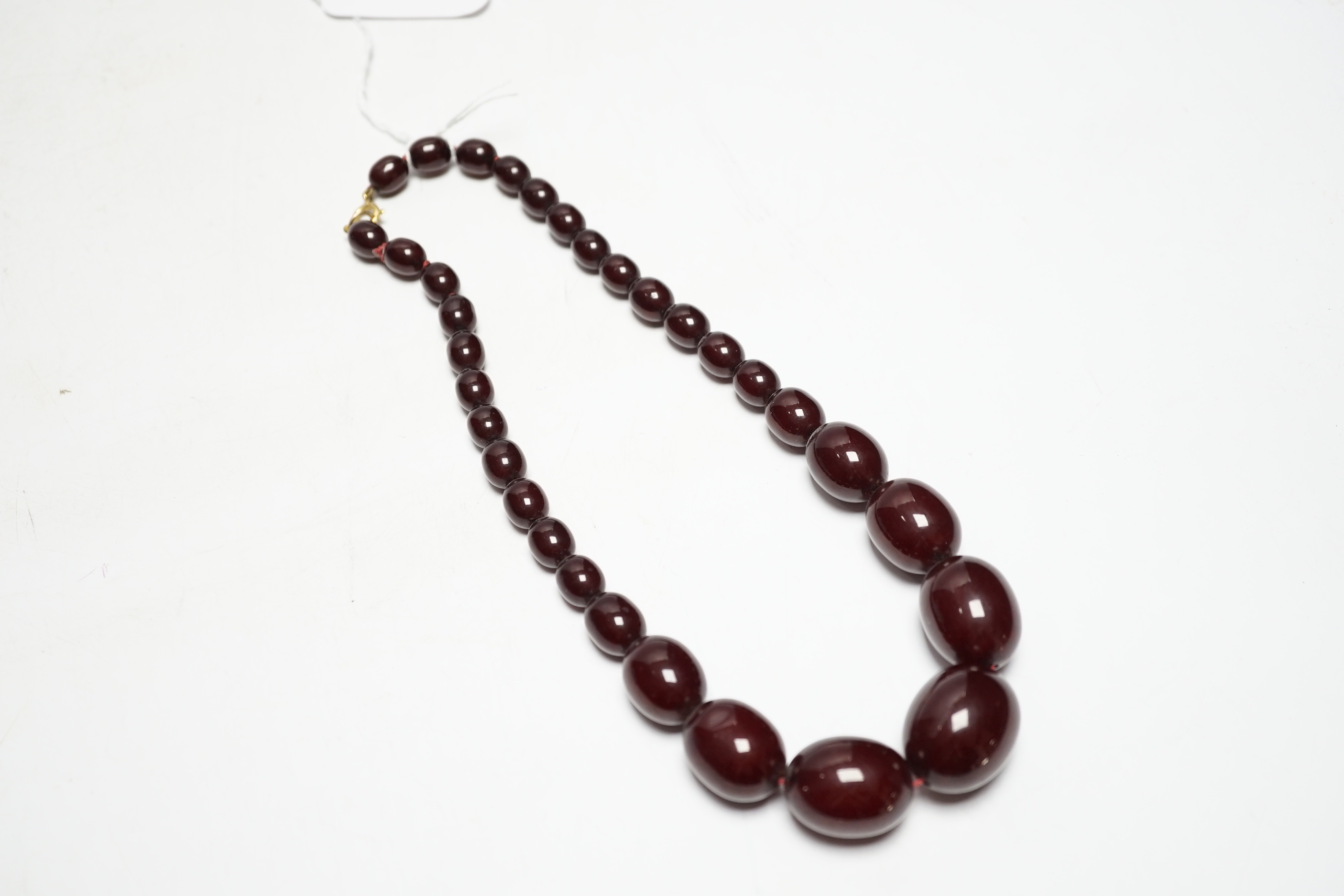 A single strand graduated oval simulated cherry amber bead necklace, 42cm, gross weight 54 grams.